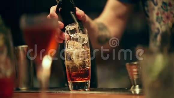 酒保在工作在杯子里混合一杯含酒精的鸡尾酒加入气泡用勺子混合最后端上视频的预览图