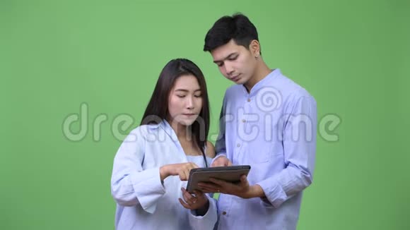 年轻的亚洲商业夫妇使用数字平板电脑一起获得好消息视频的预览图