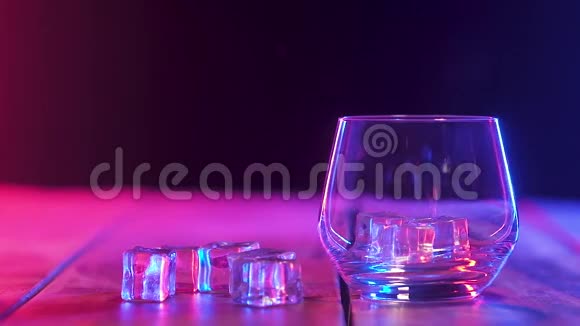 在装有冰块的玻璃杯中倒入浓香的威士忌彩色照明视频的预览图