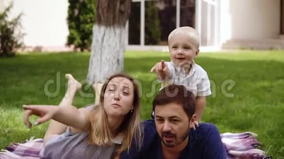 小男孩和他的父母在户外玩耍爸爸和妈妈在地上休息野餐儿子是父亲视频的预览图