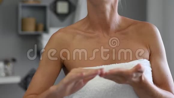 沐浴后裹着毛巾的美女正在晒黑的皮肤上涂抹沐浴露视频的预览图