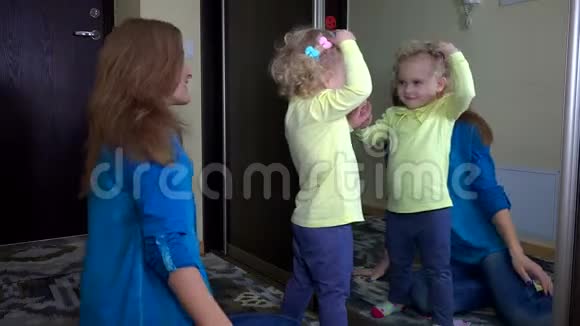 有趣的女孩和她的母亲在镜子前戴着别针视频的预览图