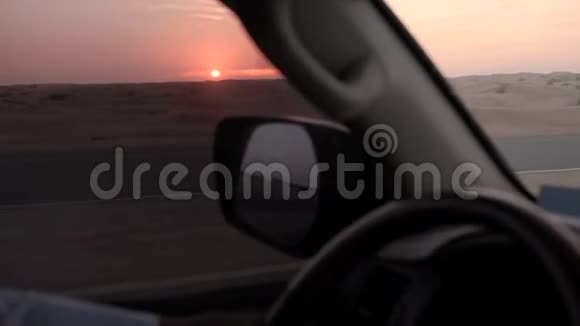 在沙漠地平线上的太阳盘上观看驾驶汽车视频的预览图