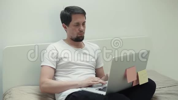 男人在网上聊天用笔记本电脑坐在卧室里视频的预览图