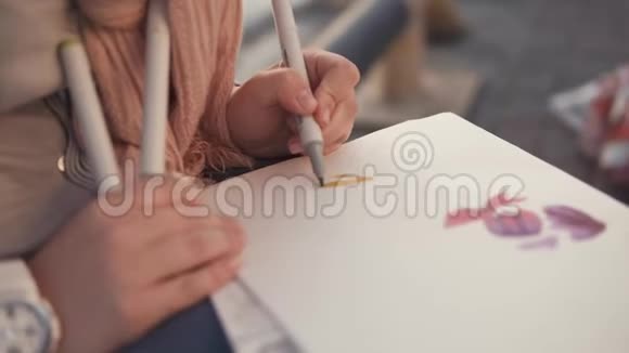 女人正在画一本素描书坐在花园里特写视频的预览图
