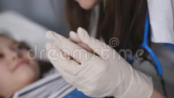 女医生在医院房间注射前安慰一个小女孩病人手的特写视频的预览图