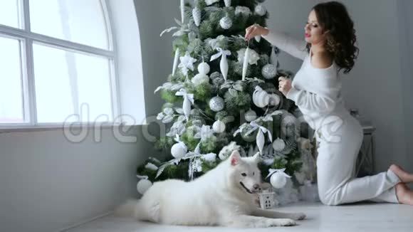 庆祝气氛幸福的年轻女子用白色装饰圣诞树视频的预览图