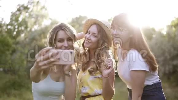 三组漂亮的女孩朋友在户外野餐他们从智能手机上拍自拍照片太阳照耀着视频的预览图