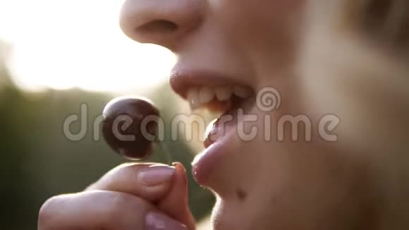 一个年轻的金发女人在吃樱桃女人拿着美味的樱桃在模糊的自然视频的预览图