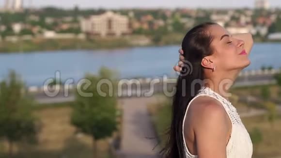 一个年轻女孩在河流和城市景观背景上的肖像视频的预览图