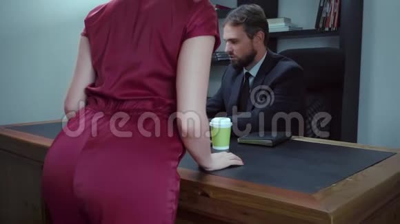 胡子商人坐在办公室的笔记本电脑前穿红衣服的女孩正试图勾引老板动作缓慢视频的预览图