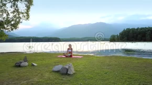 平静的湖畔宁静的画女坐在莲花的姿态视频的预览图