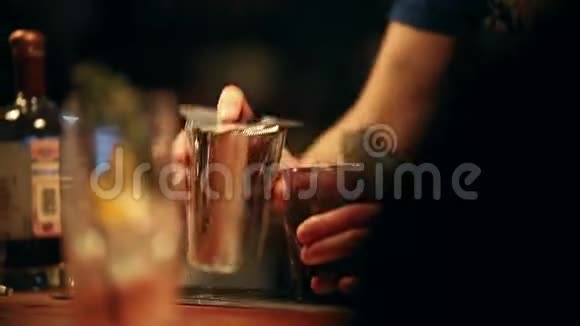 酒保在工作混合一种酒精鸡尾酒在玻璃杯中加入果汁视频的预览图
