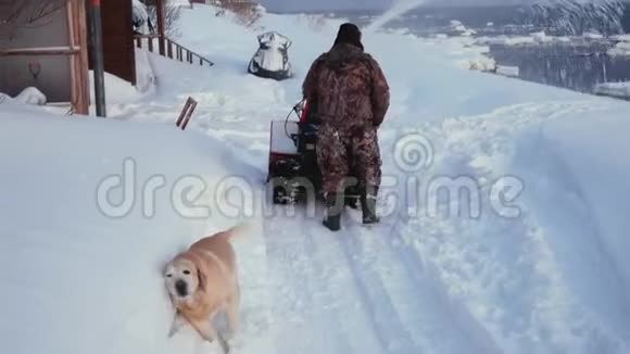 男人清洁雪机冬天的雪路和可爱的狗清洁羊毛视频的预览图