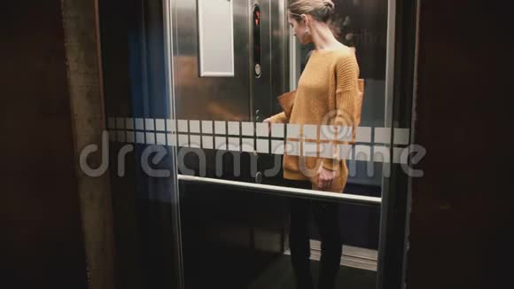 年轻自信的欧洲女人按下电梯按钮门关上她骑下来透过玻璃墙观看视频的预览图