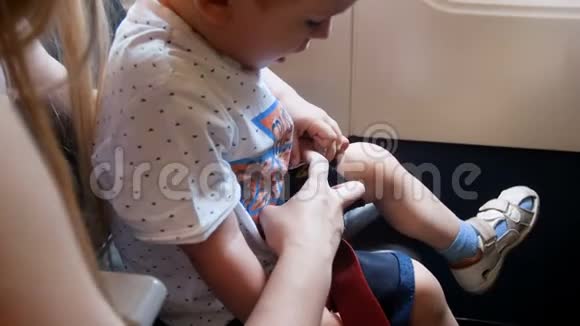 飞行前幼儿母亲在飞机上系安全带的4k特写视频视频的预览图