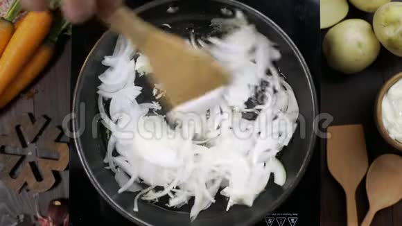 平躺视频厨师用木制厨房铲子在热锅上搅拌洋葱烹饪素食桌面视频的预览图