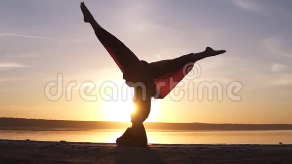 运动美丽的年轻高级瑜伽女人站在沙萨纳户外海滩美丽的日落剪影视频的预览图