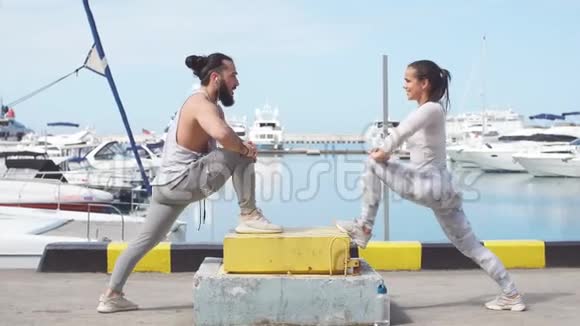 年轻漂亮的夫妇在海洋码头做伸展运动视频的预览图