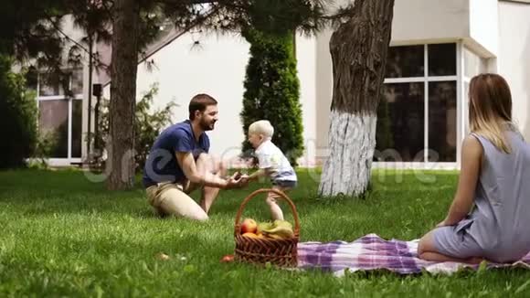 白人家庭父亲逗他的小儿子玩把锥子扔到空中在公园里闲逛野餐概念视频的预览图