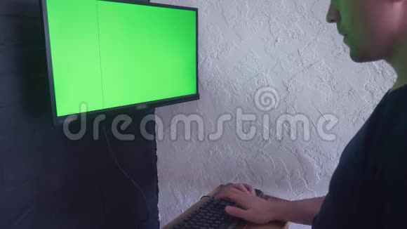年轻人正在用一个绿色屏幕模拟电脑工作4K按下键盘上的一个按钮来删除视频的预览图