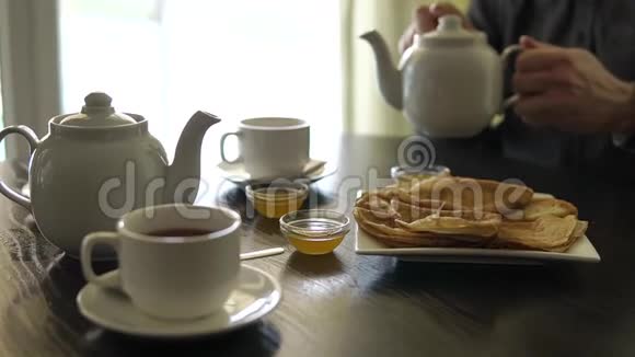 近镜头的男子的手谁倒茶从一个瓷茶壶视频的预览图
