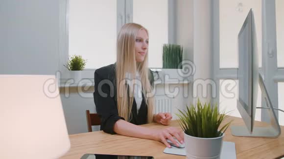 在办公室里竖起大拇指的女人坐在工作场所年轻的金发女郎穿着商务套装看着摄像机视频的预览图