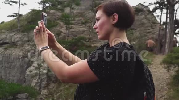 女士旅游在智能手机上拍摄美丽的绿色森林和山脉自然景观视频的预览图