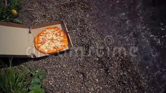 在鹅卵石海滩上有披萨的纸板箱视频的预览图