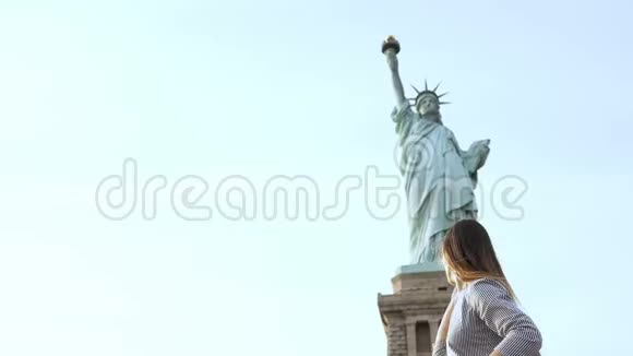 在阳光明媚的一天快乐迷人的微笑着在纽约自由女神像上打电话的欧洲旅游妇女视频的预览图
