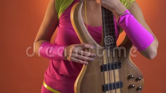 年轻女子穿着复古装带吉他橙色背景视频的预览图