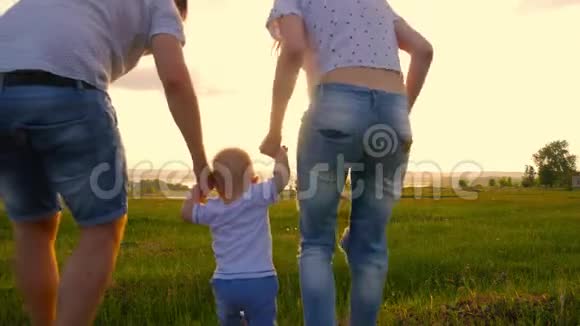 有宝宝的年轻幸福家庭日落时他们去了风景如画的绿野这个男孩是由父母抚养的日落视频的预览图
