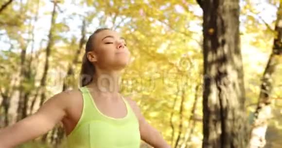 公园里的女跑步者穿着慢跑服的女人在秋天的公园里跑步后一边仰望天空一边放松视频的预览图