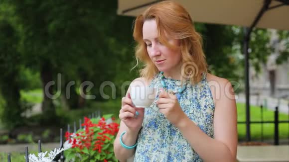 一个夏天咖啡馆里的女人正在喝茶特写站着女人穿着裙子站在公园的背景上视频的预览图