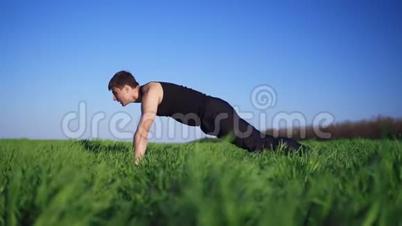 年轻人做俯卧撑手臂伸出来锻炼身体英俊的白种人绿草如茵晴天视频的预览图