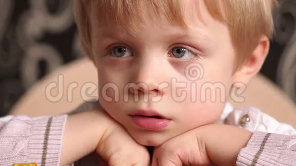 餐桌上厨房里悲伤的小男孩的画像视频的预览图