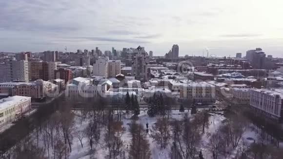 鸟瞰冬季城市景观与建筑物公园和道路剪辑有雪覆盖屋顶的城镇的无人视野视频的预览图