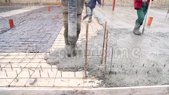 在混凝土模板上用水泥搅拌机浇筑混凝土一群工人在一个建筑上浇筑混凝土视频的预览图