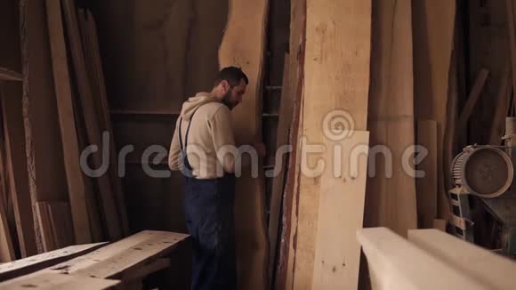 一个满是木材的木工车间的工人选择合适的材料进行工作高木片设备视频的预览图