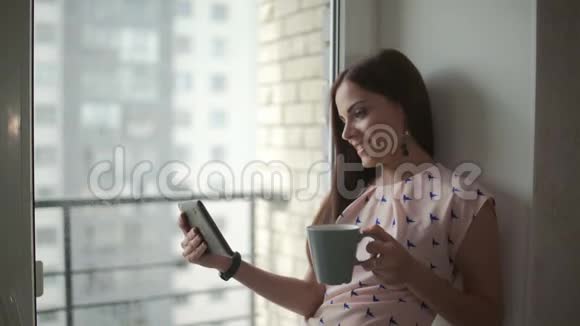 女人在平板电脑上看电影喝咖啡视频的预览图