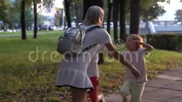 两个白种人男孩跑到母亲手拥抱她和旋转视频的预览图