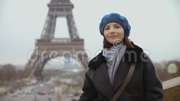 在巴黎埃菲尔铁塔附近一位身穿贝雷帽和冬衣的妇女微笑着摆姿势视频的预览图