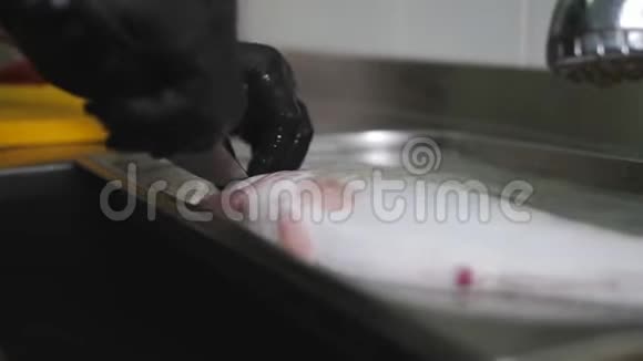厨师戴着黑色手套在烹饪前清洗鱼视频的预览图