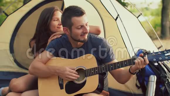 坐在露营帐篷里的男女朋友弹吉他视频的预览图