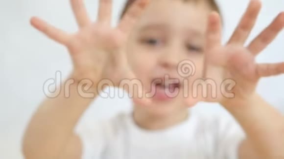 快乐的孩子在白色的背景上展示他的双手特写这个男孩向前伸展手臂视频的预览图