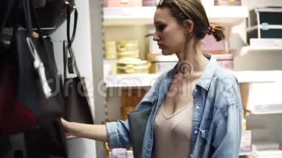 一个头发束成一束头戴眼镜的女孩选择一个袋子商店里皮手提包的配置视频的预览图