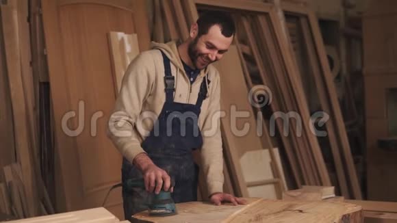 工人正在用一台机器打磨一块木头用于手中的研磨后面的木质材料视频的预览图