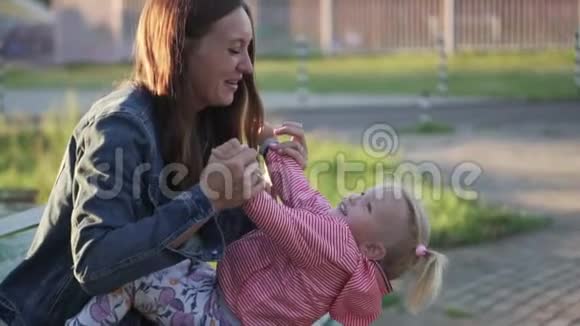妈妈和一个小女孩坐在公园的长凳上他们玩得很开心视频的预览图