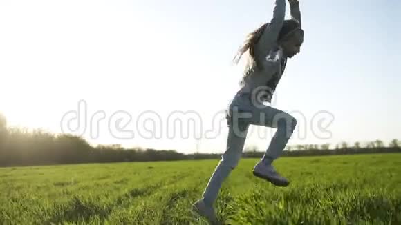 长发的穿着白色衣服的小女孩正在户外玩耍她做翻筋斗大片绿色的草地乐趣和乐趣视频的预览图