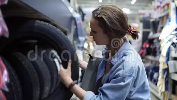 大型购物中心可爱的女孩选择汽车轮胎考试买方一排排不同的汽车轮胎侧视图视频的预览图